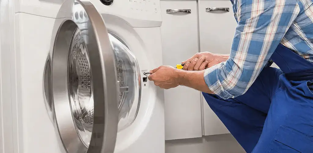 Handyman repairing a clothes dryer and checking electrical connections in Miami, FL