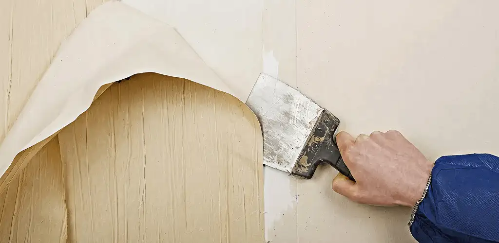 Handyman removing wallpaper with a scraper for wall preparation in Miami, FL