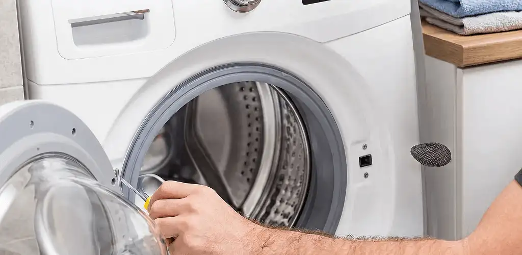 Handyman repairing a front-load washing machine and inspecting the drum in Miami, FL