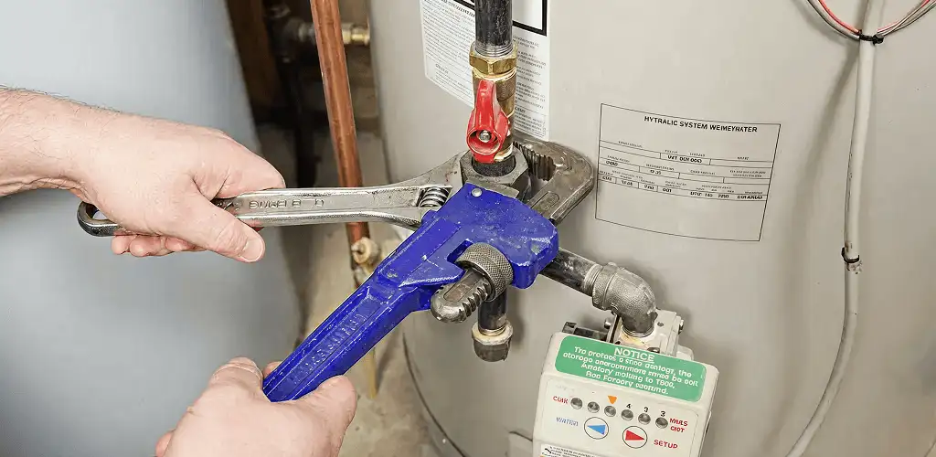 Water heater repair technician tightening the shutoff valve and supply line in Miami, FL